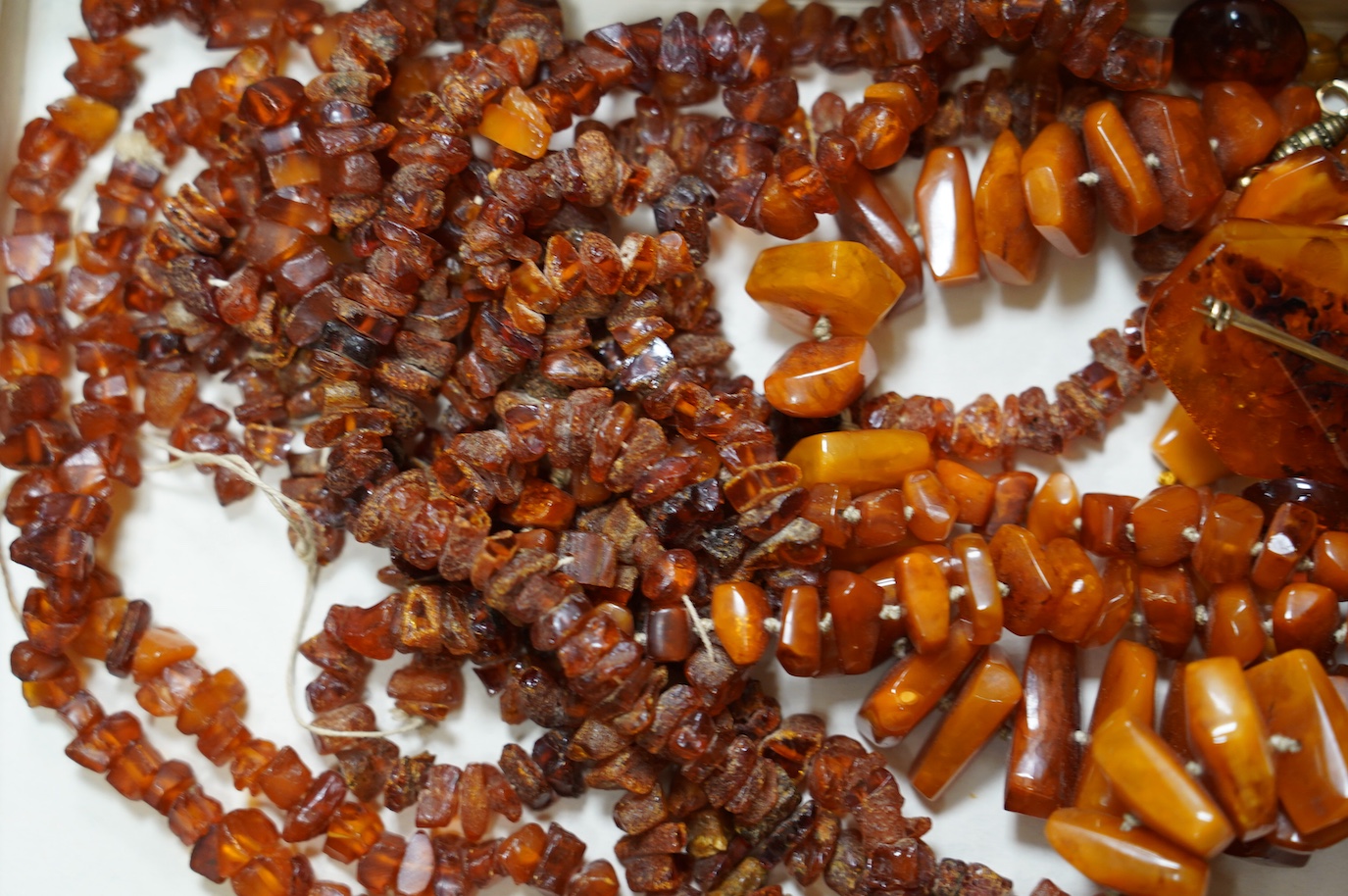 Five assorted single strand amber necklaces, including jagged pebble and unpolished, longest 176cm, together with two mounted amber rings, a pair of ear clips and a brooch, gross weight 357 grams. Condition - poor to fai